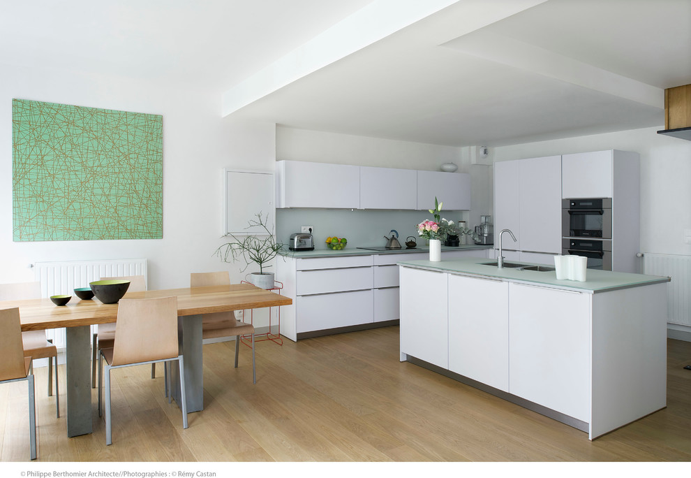 This is an example of a large contemporary l-shaped open plan kitchen in Paris with white cabinets and an island.