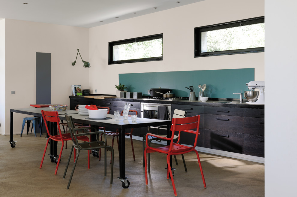 Пример оригинального дизайна: большая прямая кухня в современном стиле с обеденным столом, одинарной мойкой, плоскими фасадами, темными деревянными фасадами, синим фартуком, техникой из нержавеющей стали и бетонным полом без острова