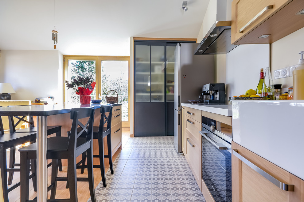 Immagine di una cucina stile americano di medie dimensioni con lavello stile country, ante in legno chiaro, paraspruzzi bianco, elettrodomestici in acciaio inossidabile, pavimento in cementine e pavimento multicolore