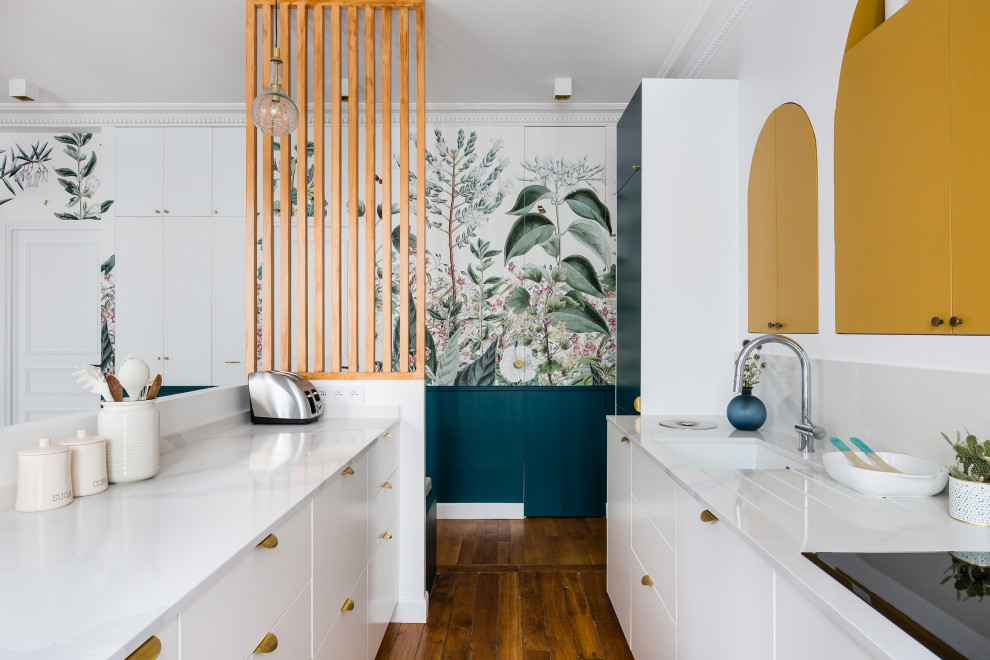 Zweizeilige Moderne Küche mit Unterbauwaschbecken, flächenbündigen Schrankfronten, weißen Schränken, braunem Holzboden, Kücheninsel, braunem Boden, weißer Arbeitsplatte und Tapete in Paris