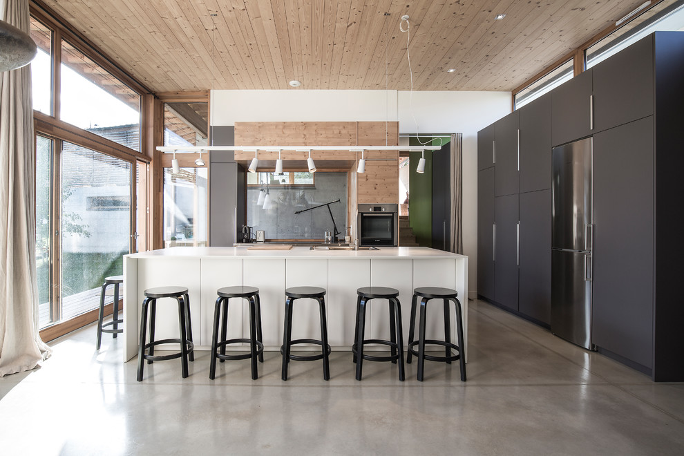 Large trendy galley concrete floor and gray floor eat-in kitchen photo in Grenoble with flat-panel cabinets, glass sheet backsplash, stainless steel appliances, an island, a single-bowl sink and gray backsplash