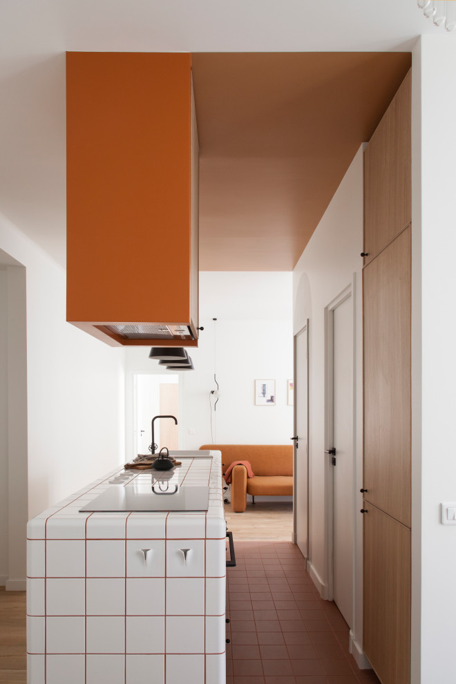 Idéer för mellanstora minimalistiska linjära vitt kök med öppen planlösning, med en integrerad diskho, luckor med profilerade fronter, skåp i ljust trä, kaklad bänkskiva, grått stänkskydd, integrerade vitvaror, klinkergolv i terrakotta, en köksö och brunt golv