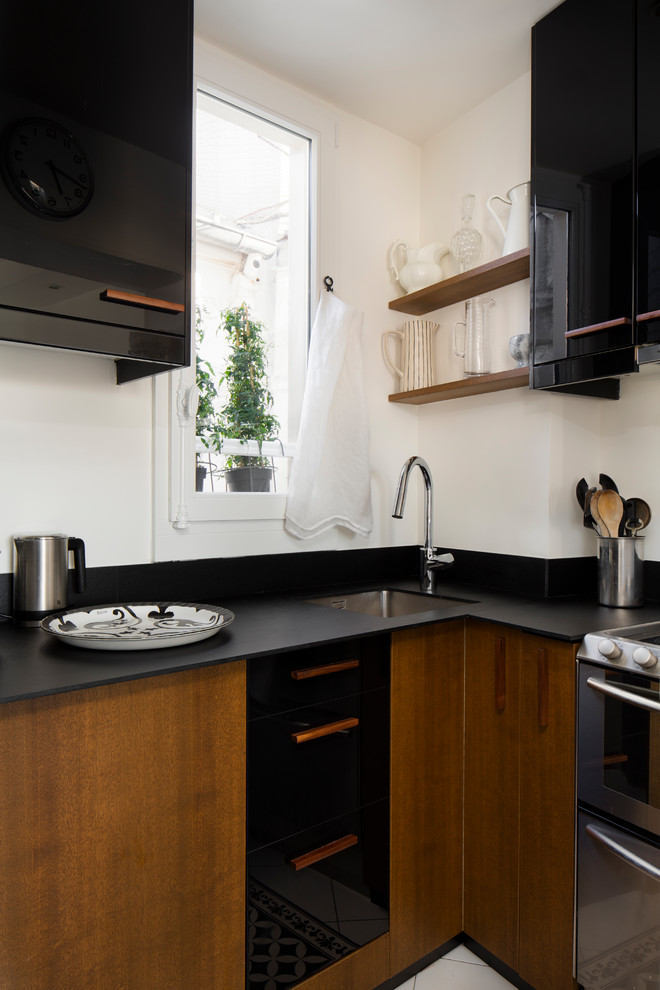 Ispirazione per una cucina a L contemporanea con lavello sottopiano, ante lisce, ante nere e top nero
