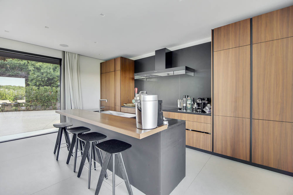 Large contemporary galley kitchen in Marseille with a submerged sink, flat-panel cabinets, medium wood cabinets, grey splashback, integrated appliances, an island, grey floors and grey worktops.
