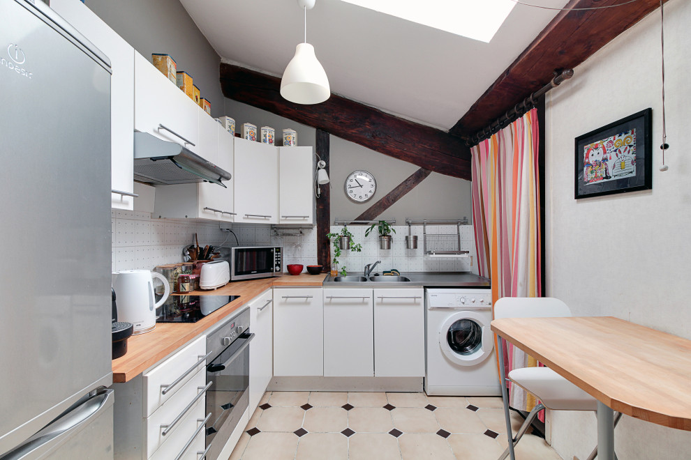 Moderne Küche in L-Form mit integriertem Waschbecken, flächenbündigen Schrankfronten, weißen Schränken, Arbeitsplatte aus Holz, Küchenrückwand in Weiß, weißen Elektrogeräten, beigem Boden, brauner Arbeitsplatte und gewölbter Decke in Lyon