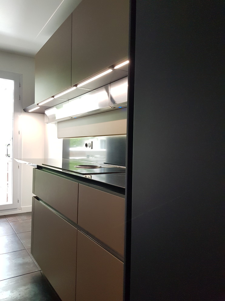Photo of a small modern galley enclosed kitchen in Paris with a submerged sink, beaded cabinets, blue cabinets, quartz worktops, black splashback, integrated appliances, ceramic flooring, no island, brown floors and black worktops.