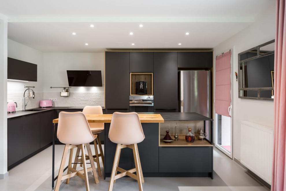 リヨンにある高級な中くらいなコンテンポラリースタイルのおしゃれなキッチン (シェーカースタイル扉のキャビネット、白いキッチンパネル、レンガのキッチンパネル、カラー調理設備、グレーの床、黒いキッチンカウンター) の写真