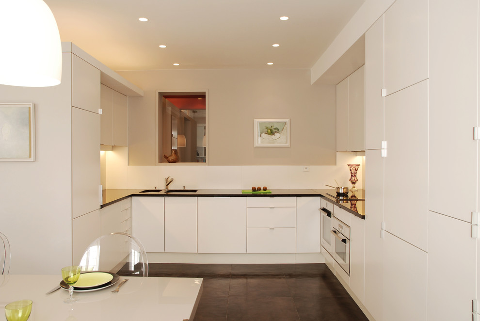 Foto di una cucina design di medie dimensioni con lavello sottopiano, ante lisce, ante bianche, elettrodomestici da incasso e nessuna isola