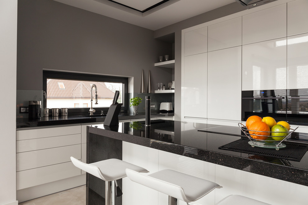 Idee per una cucina contemporanea di medie dimensioni con lavello sottopiano, ante bianche, top in granito e elettrodomestici neri