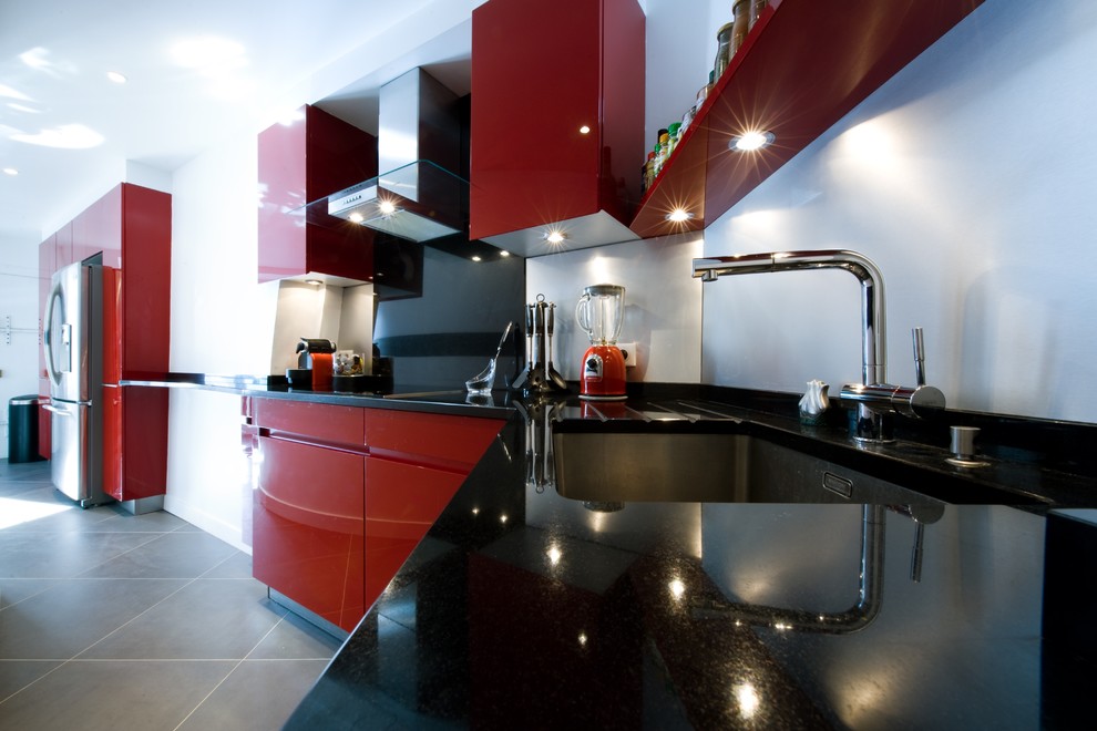 Exemple d'une très grande cuisine moderne avec un plan de travail en granite, aucun îlot et des portes de placard rouges.