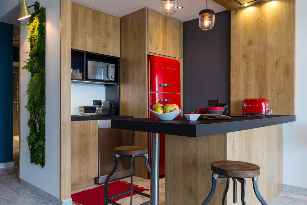 Diseño de cocina lineal contemporánea con armarios con paneles lisos, puertas de armario de madera oscura, electrodomésticos de colores, península, suelo gris y encimeras negras