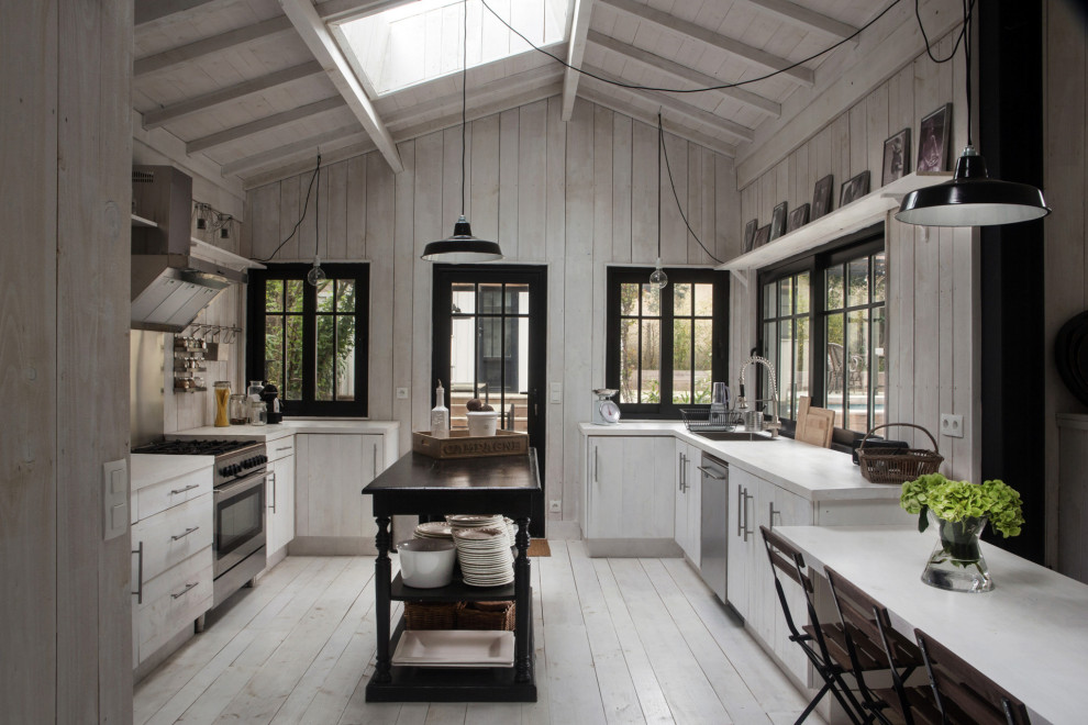 Bild på ett stort medelhavsstil vit vitt kök, med en nedsänkt diskho, släta luckor, vita skåp, grått stänkskydd, stänkskydd i trä, målat trägolv, en köksö och grått golv