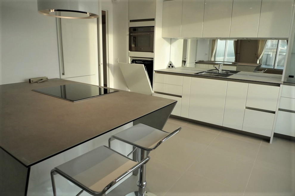 Photo of a medium sized single-wall open plan kitchen in Nantes with a single-bowl sink, flat-panel cabinets, white cabinets, integrated appliances, ceramic flooring, a breakfast bar, grey floors and grey worktops.