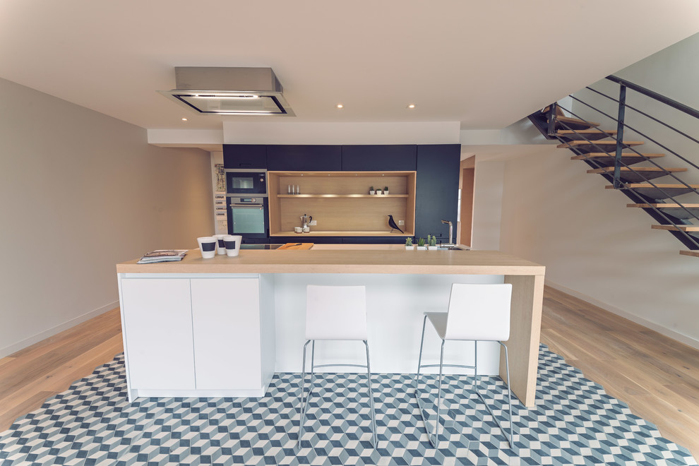 Medium sized contemporary galley open plan kitchen in Rennes with a single-bowl sink, beaded cabinets, black cabinets, quartz worktops, white splashback, stainless steel appliances, cement flooring, an island and black floors.