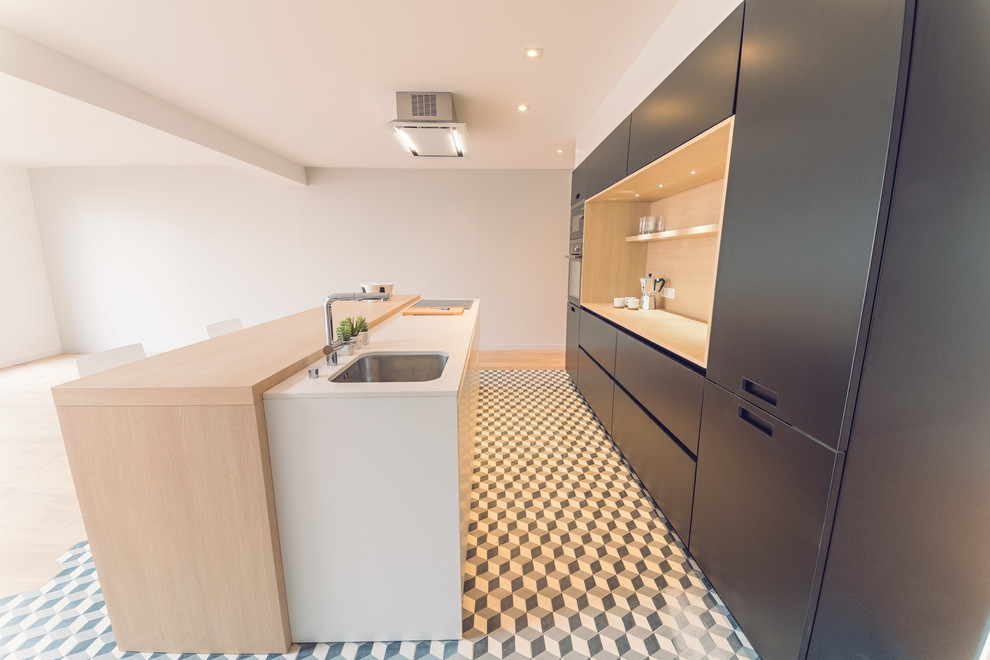 Design ideas for a medium sized contemporary galley open plan kitchen in Rennes with a single-bowl sink, beaded cabinets, black cabinets, quartz worktops, white splashback, stainless steel appliances, cement flooring, an island and black floors.