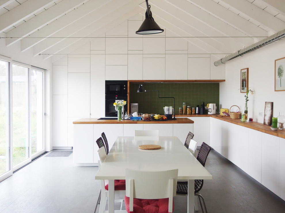 Bild på ett stort funkis kök, med vita skåp, träbänkskiva, grönt stänkskydd, stänkskydd i keramik, svarta vitvaror, vinylgolv, en köksö och släta luckor