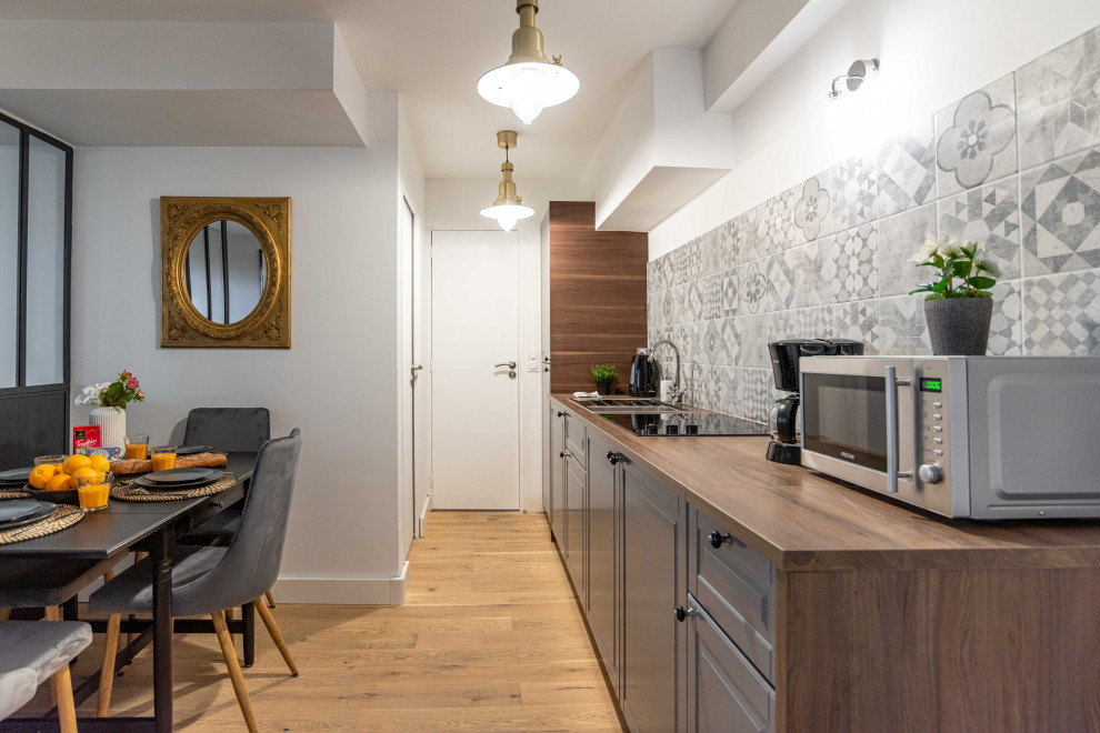 Photo of a small traditional single-wall kitchen/diner in Paris with a built-in sink, raised-panel cabinets, grey cabinets, wood worktops, grey splashback, no island, beige floors and brown worktops.