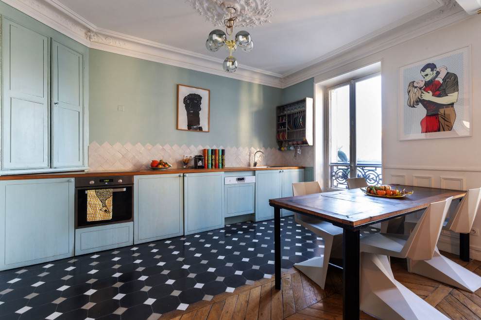 Пример оригинального дизайна: прямая кухня-гостиная в стиле фьюжн с плоскими фасадами, синими фасадами, деревянной столешницей, техникой из нержавеющей стали, черным полом и коричневой столешницей без острова
