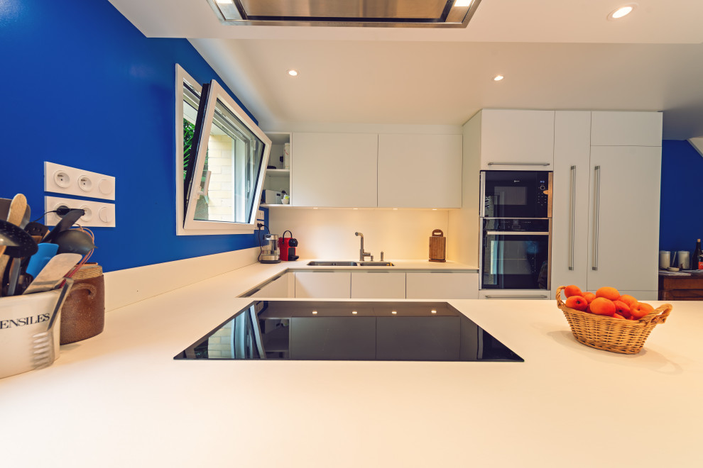 Cette image montre une grande cuisine ouverte design en U avec une crédence blanche, un électroménager en acier inoxydable et un sol en carrelage de céramique.