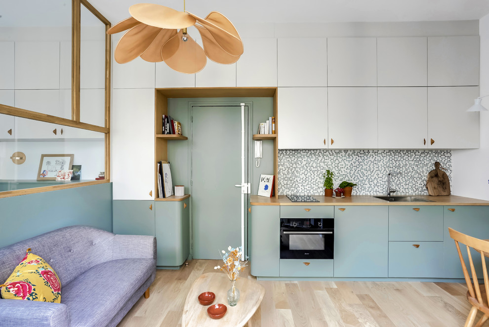 Inspiration for a scandinavian single-wall light wood floor and beige floor open concept kitchen remodel in Paris with a single-bowl sink, flat-panel cabinets, wood countertops, multicolored backsplash, mosaic tile backsplash, black appliances and no island