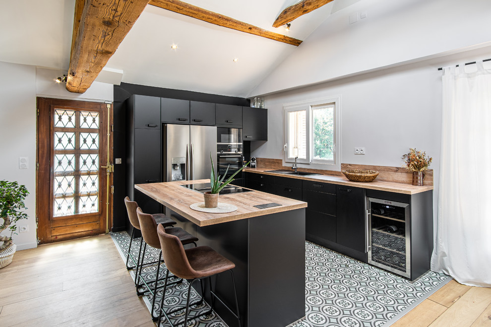 Scandinavian kitchen in Lyon with flat-panel cabinets, black cabinets, wood worktops, stainless steel appliances, an island and multi-coloured floors.