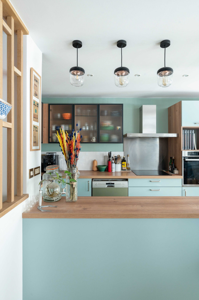 Aménagement d'une cuisine parallèle éclectique avec un placard à porte plane, des portes de placard bleues, un plan de travail en bois, une péninsule et un plan de travail marron.