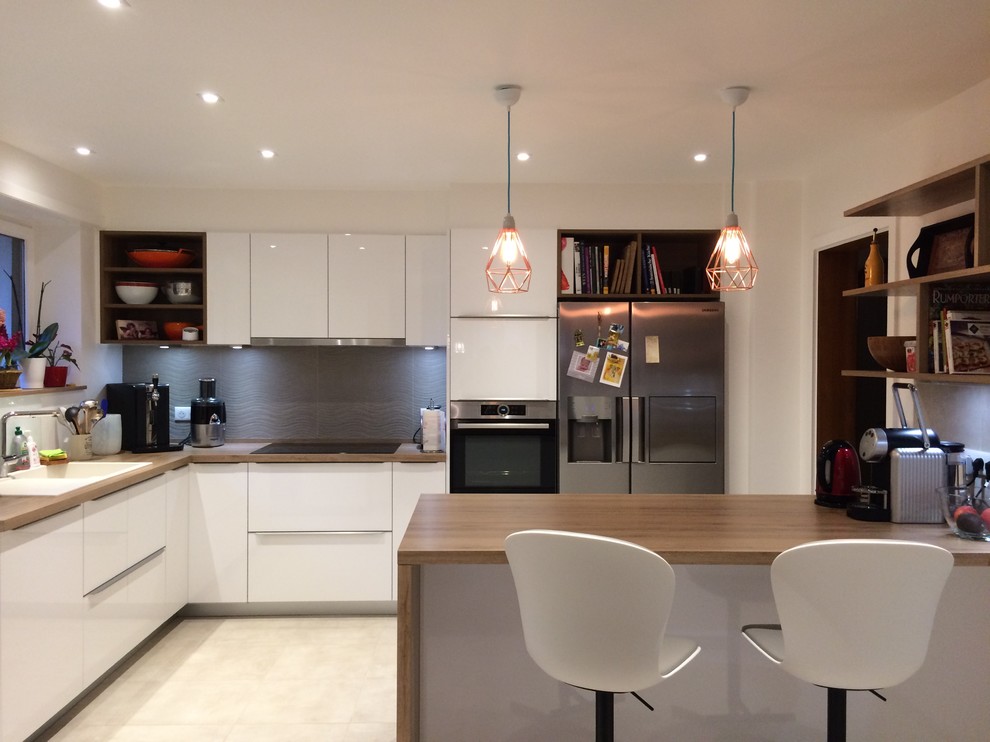 This is an example of a large contemporary l-shaped kitchen/diner in Strasbourg with a single-bowl sink, flat-panel cabinets, white cabinets, laminate countertops, grey splashback, stone tiled splashback, stainless steel appliances, ceramic flooring, an island, grey floors and brown worktops.