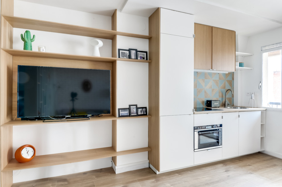 This is an example of a small scandi single-wall open plan kitchen in Paris with wood worktops, blue splashback, integrated appliances, no island, a built-in sink, white cabinets and light hardwood flooring.