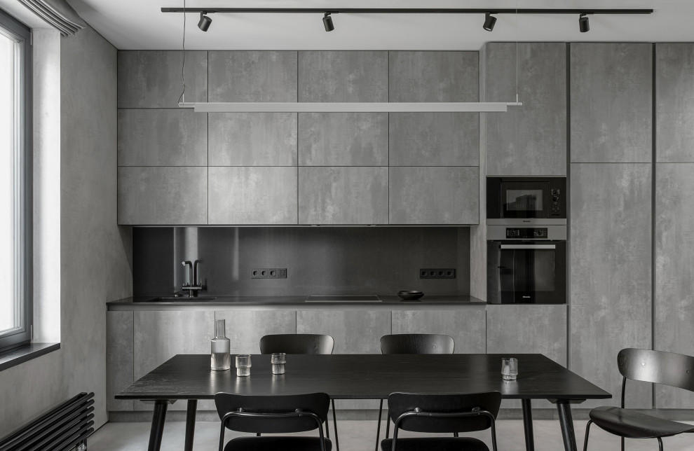 Идея дизайна: параллельная кухня-гостиная среднего размера в стиле лофт с монолитной мойкой, столешницей из ламината, черным фартуком, техникой под мебельный фасад и черной столешницей