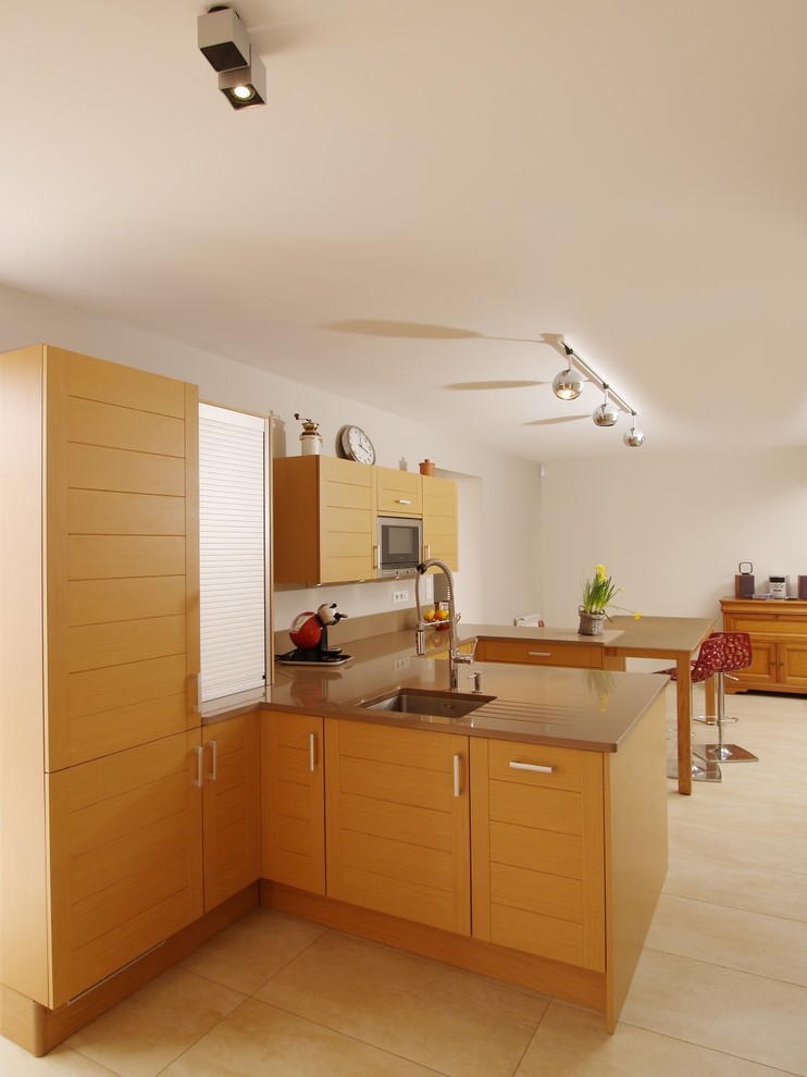 Modern inredning av ett stort u-kök, med en integrerad diskho, luckor med infälld panel, skåp i ljust trä, bänkskiva i kvartsit, färgglada vitvaror, klinkergolv i keramik, en halv köksö och beiget golv