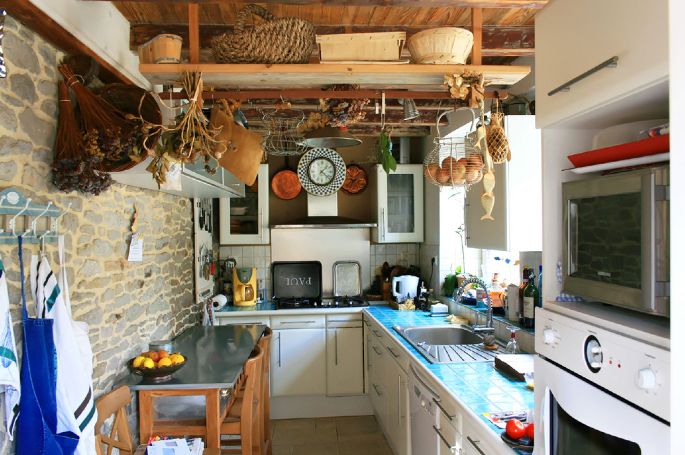 Immagine di una piccola cucina a L eclettica chiusa con lavello da incasso, ante lisce, ante bianche, top piastrellato, paraspruzzi bianco e elettrodomestici bianchi