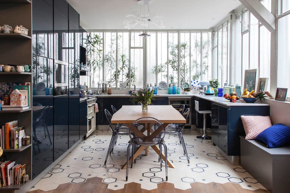 На фото: п-образная кухня в современном стиле с обеденным столом, плоскими фасадами, синими фасадами, техникой из нержавеющей стали, полом из керамической плитки, разноцветным полом и красивой плиткой без острова с