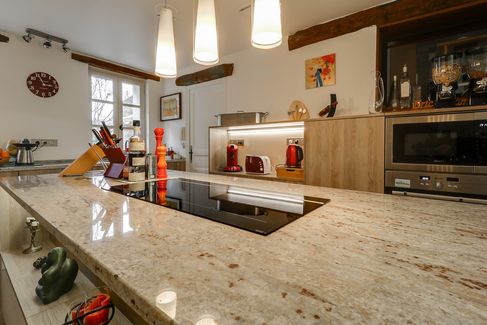 Contemporary kitchen in Paris with light wood cabinets, granite worktops, stainless steel appliances and an island.