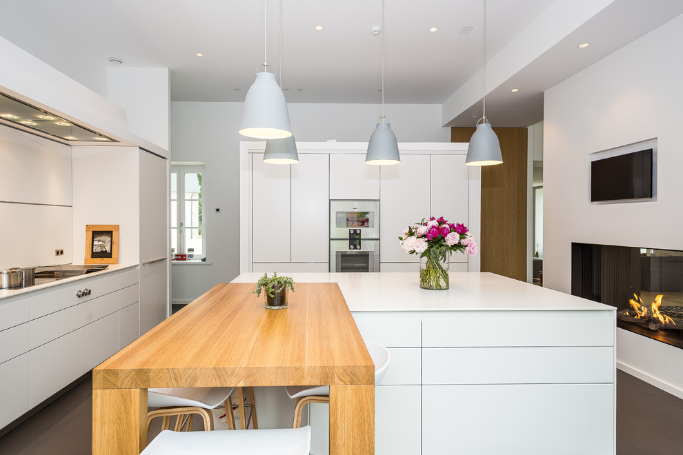 Immagine di una grande cucina minimal chiusa con lavello a vasca singola, ante bianche, paraspruzzi bianco, elettrodomestici in acciaio inossidabile, pavimento marrone e top bianco