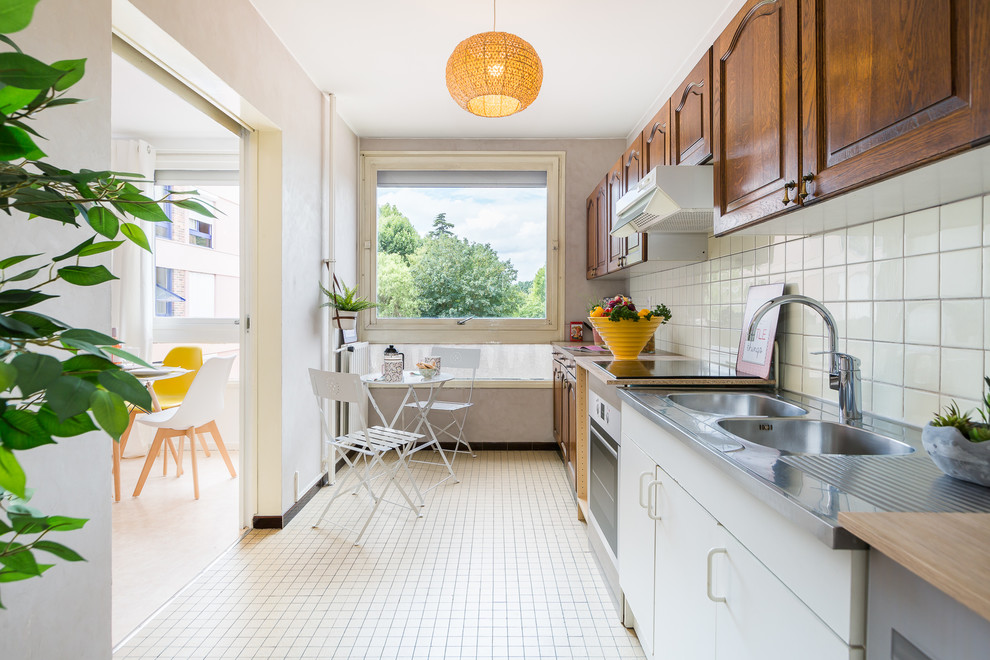 Scandinavian single-wall enclosed kitchen in Paris with a built-in sink, raised-panel cabinets, dark wood cabinets, wood worktops, white splashback, ceramic splashback, no island, white floors and beige worktops.