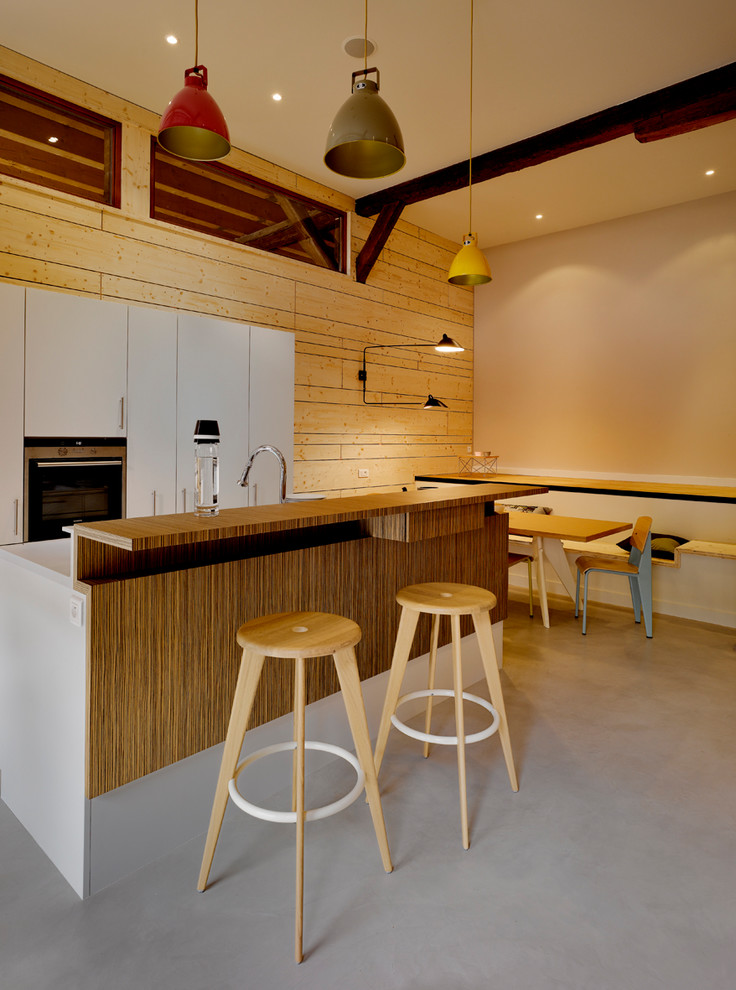 Ispirazione per un cucina con isola centrale design con ante lisce, ante bianche, pavimento in cemento e pavimento grigio