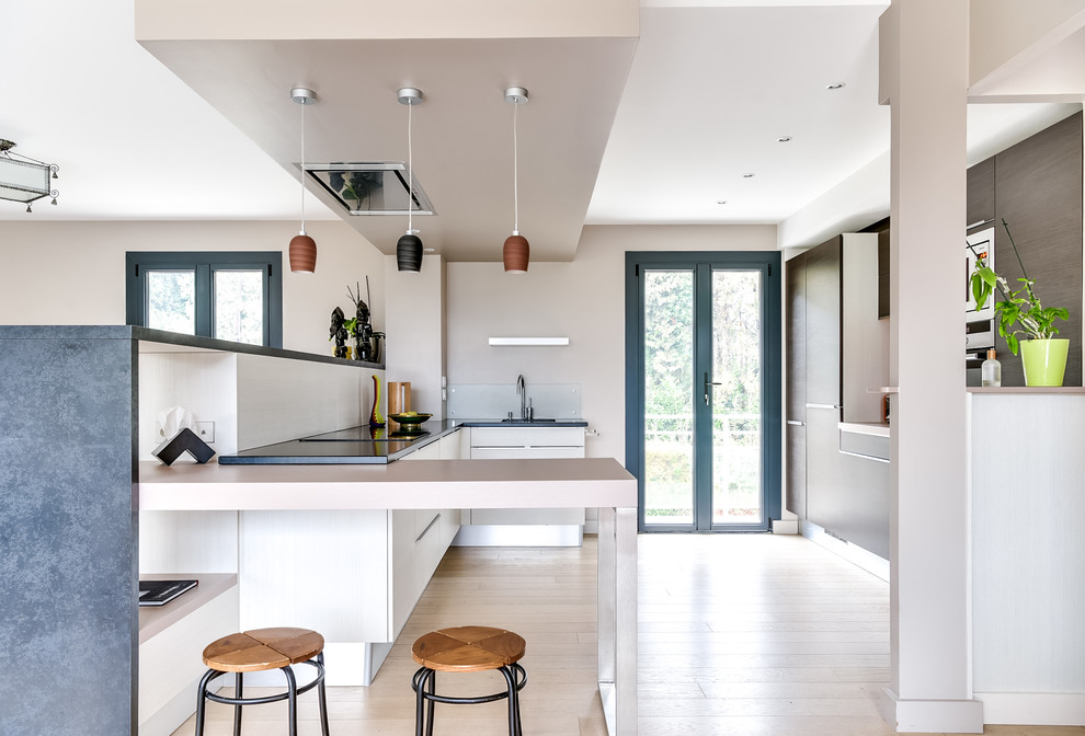 Example of a large minimalist l-shaped light wood floor and beige floor eat-in kitchen design in Lyon with flat-panel cabinets, medium tone wood cabinets, granite countertops, a peninsula, an undermount sink, orange backsplash, wood backsplash, stainless steel appliances and gray countertops