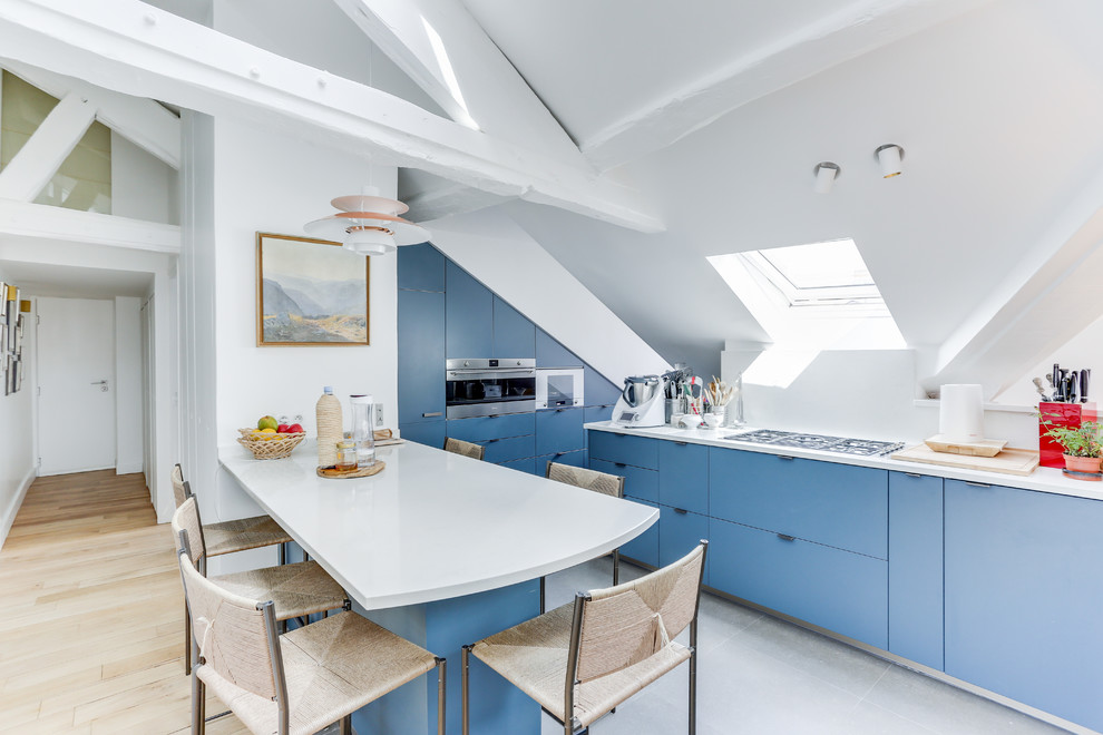 Источник вдохновения для домашнего уюта: кухня в морском стиле с плоскими фасадами, синими фасадами, техникой из нержавеющей стали, полуостровом, серым полом, белой столешницей и окном
