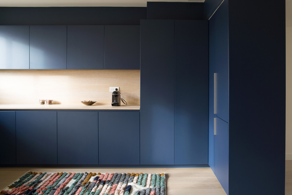 Inspiration for a contemporary l-shaped kitchen in Paris with flat-panel cabinets, blue cabinets, wood worktops, beige splashback, wood splashback, light hardwood flooring, beige floors and beige worktops.