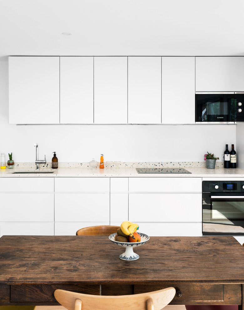 Diseño de cocina lineal minimalista abierta con fregadero bajoencimera, encimera de terrazo, salpicadero multicolor, suelo de madera clara y encimeras multicolor