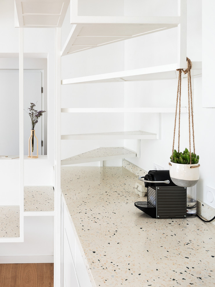 Modelo de cocina minimalista abierta con fregadero bajoencimera, encimera de terrazo, salpicadero multicolor, suelo de madera clara y encimeras multicolor