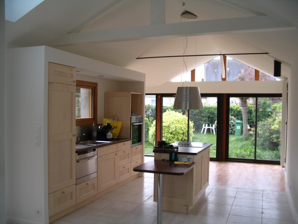 Foto di una cucina design con lavello sottopiano, ante in legno chiaro, paraspruzzi grigio, elettrodomestici in acciaio inossidabile e pavimento con piastrelle in ceramica