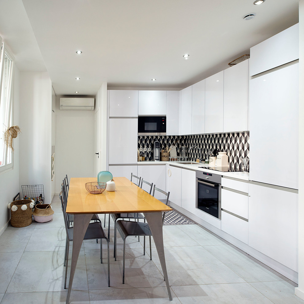 Bild på ett funkis kök och matrum, med en undermonterad diskho, släta luckor, vita skåp, flerfärgad stänkskydd, rostfria vitvaror och grått golv
