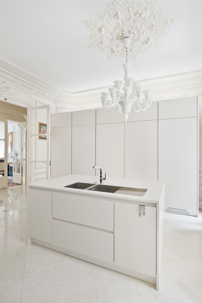 Geschlossene, Mittelgroße Moderne Küche mit Doppelwaschbecken, flächenbündigen Schrankfronten, weißen Schränken, Marmorboden und Kücheninsel in Paris