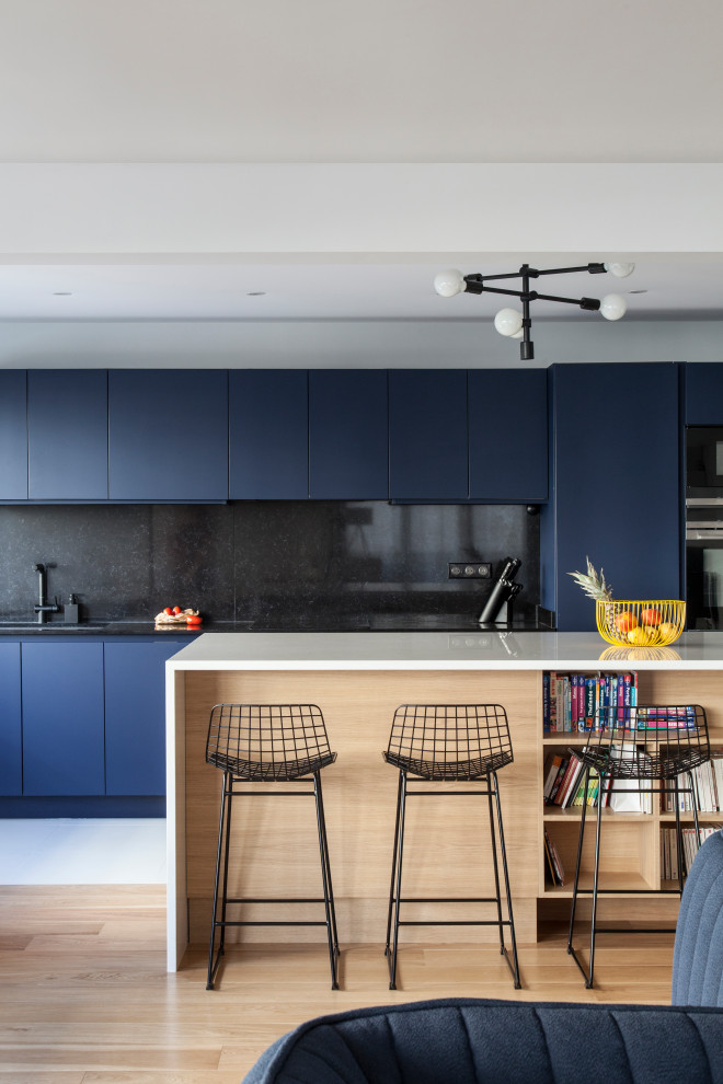 Large contemporary single-wall open plan kitchen in Other with a double-bowl sink, blue cabinets, quartz worktops, black splashback, black appliances, ceramic flooring, an island, white floors and white worktops.