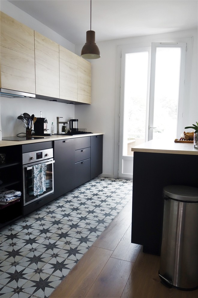 Moderne Küche mit schwarzen Schränken, Arbeitsplatte aus Holz, Küchenrückwand in Weiß, Küchengeräten aus Edelstahl, Zementfliesen für Boden und schwarzem Boden in Marseille