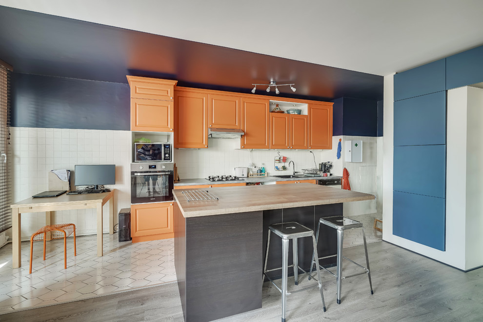 Einzeilige Stilmix Küche mit Doppelwaschbecken, profilierten Schrankfronten, orangefarbenen Schränken, Küchenrückwand in Weiß, Kücheninsel und grauer Arbeitsplatte in Lyon