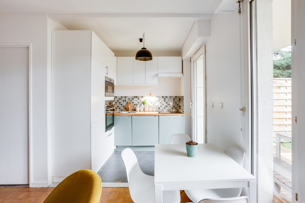 Bild på ett litet minimalistiskt kök, med en undermonterad diskho, släta luckor, gröna skåp, träbänkskiva, grönt stänkskydd, stänkskydd i keramik, integrerade vitvaror, skiffergolv och grått golv