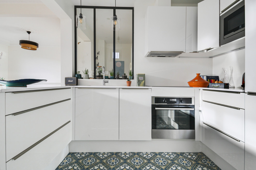 Medium sized modern u-shaped open plan kitchen in Paris with a submerged sink, engineered stone countertops, white splashback, integrated appliances, cement flooring, an island, blue floors, white worktops, beaded cabinets and white cabinets.
