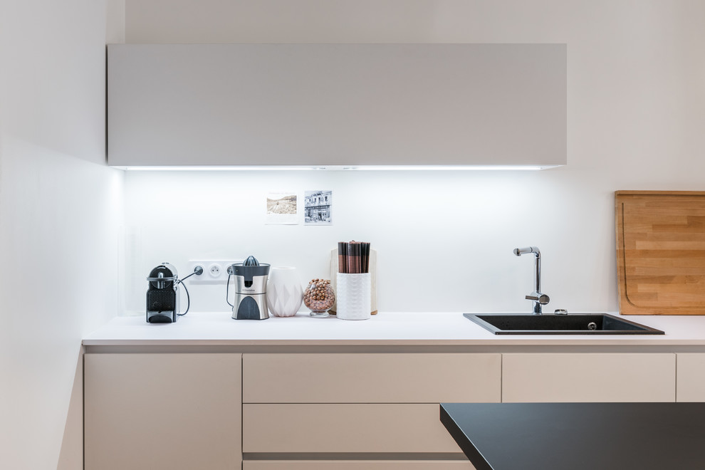 Foto på ett avskilt, stort funkis parallellkök, med en enkel diskho, vita skåp, laminatbänkskiva, rostfria vitvaror, mörkt trägolv och en köksö